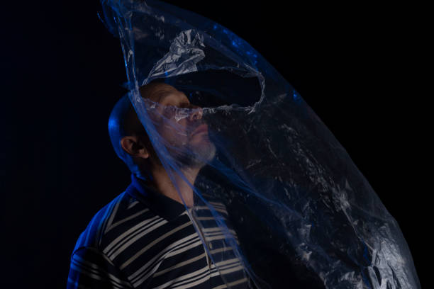 istock Mature man with a transparent plastic blue bag flying over his head and face. 1437371619