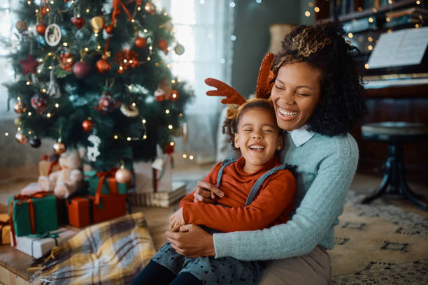 Joyful black mother and daughter laughing on Christmas day at home. stock photo