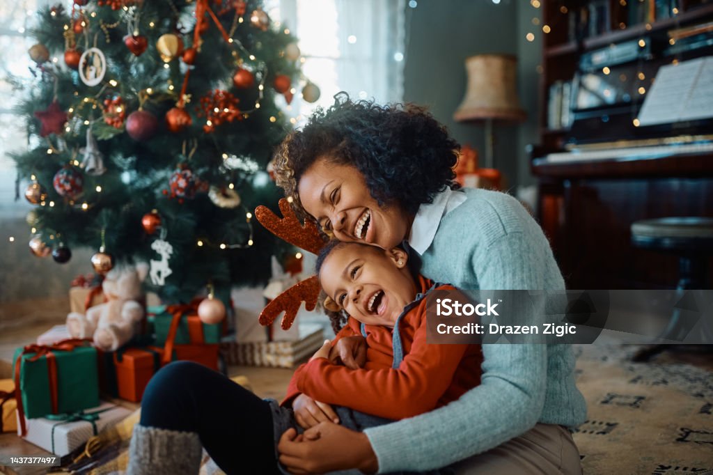 Cheerful African American mother and daughter having fun on Christmas day at home. Happy African American mother and daughter laughing and having fun while spending Christmas together at home. Christmas Stock Photo