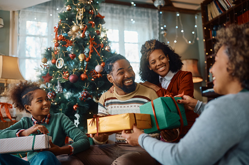 Happy African American multi-generation family exchanging gifts at Christmas.