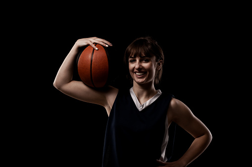 Teenage athlete (young woman) posing with basketball against white background.