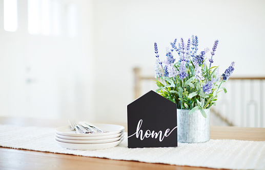 Dining room table with home sign and lavender plant in a bright modern home setting. Shot with space for copy