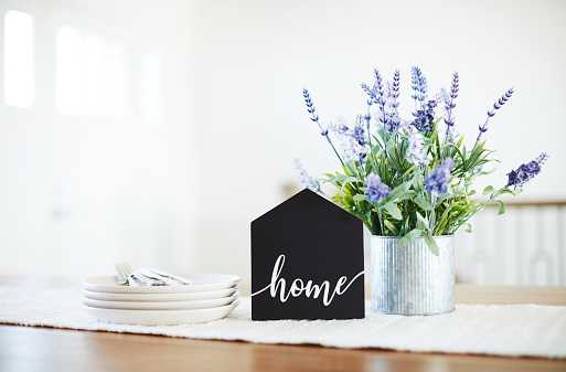 Dining room table with home sign and lavender plant in a bright modern home setting. Shot with space for copy