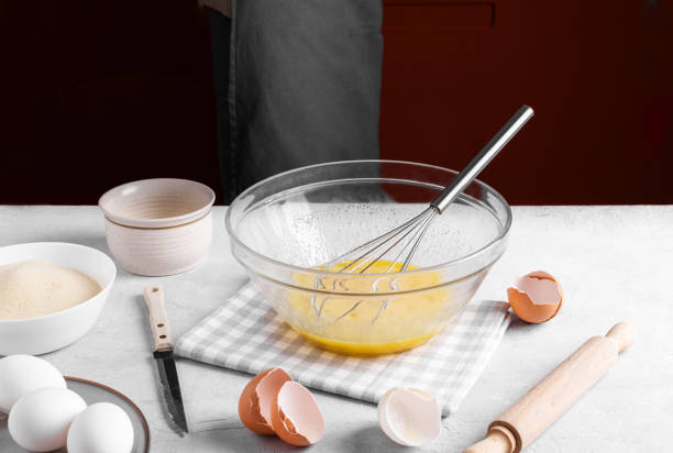istock Bowl with fresh eggs and whisk for whipping and ingredients for baking a pie on a gray table in the kitchen, home bake 1437380262