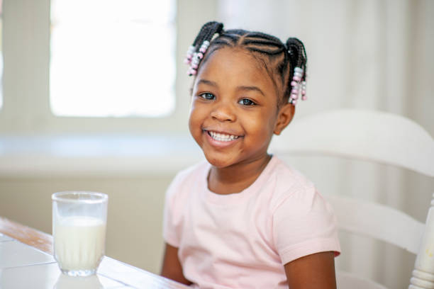 niña africana disfrutando de un vaso de leche - beauty beautiful braids dairy product fotografías e imágenes de stock
