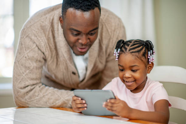 istock Little Girl with Her Father Playing on a Tablet 1437381084