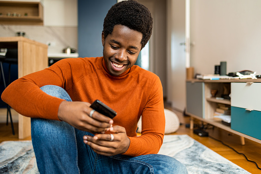 Young African American man using mobile phone at home