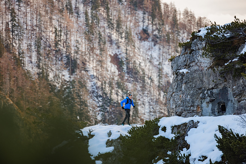A well active, athletic Caucasian trail runner running outside in winter mountains.