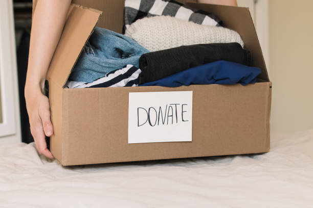 istock Woman's hands holding a box full of clothes to donate. 1437392769