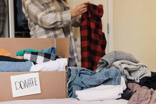 istock Box with clothing and text donate and woman sorting her clothing. 1437392774