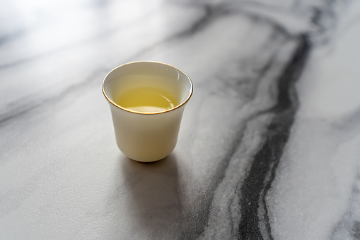 Tea in a white ceramic teacup on a textured marble