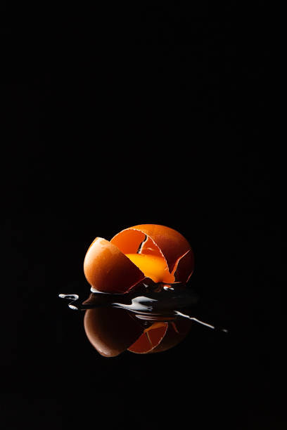 An egg falls and cracks, the shell breaks, and the egg runs out - stock photo