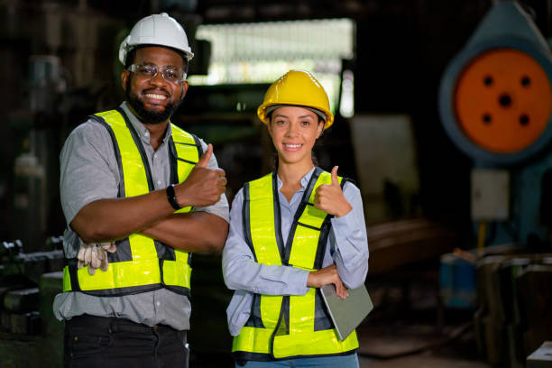 trabalhadores de fábrica afro-americanos, homens e mulheres mostram polegares para cima e olham para a câmera sorrindo durante o trabalho na área de trabalho da indústria. - control panel factory control machine - fotografias e filmes do acervo