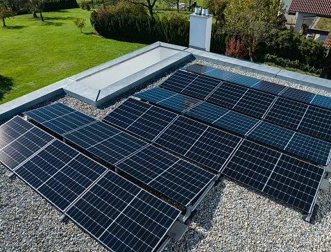 New Solar Panels - Photovoltaic System installed on top of flat roof on modern Private Home Green Building. Aerial Drone Point of View. Green Energy - Sustainable Energy at Home Concept. Southern Germany, Europe