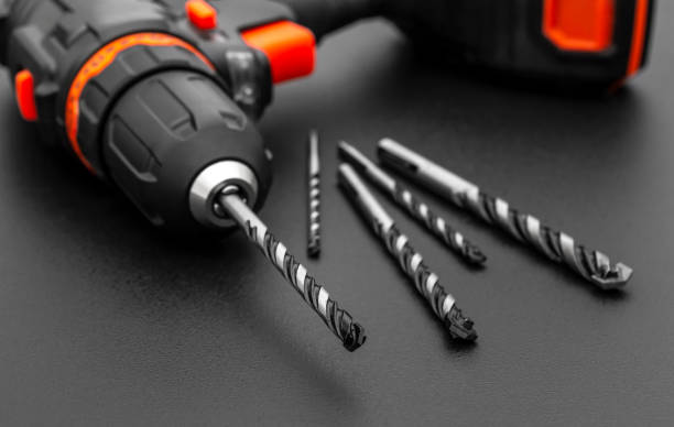 Accumulator drill with drill bits on black. Close up. stock photo