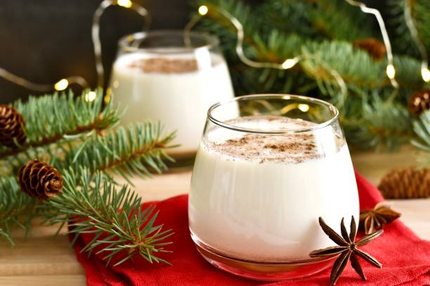 eierlikör in gläsern mit sternanis, zimt, chrismaszweig und girlande auf roter serviette auf holztisch. selektiver fokus. traditionelles weihnachtsgetränk - zimtstern stock-fotos und bilder