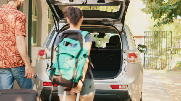 istock Casual couple putting voyage baggage inside vehicle trunk 1437420673