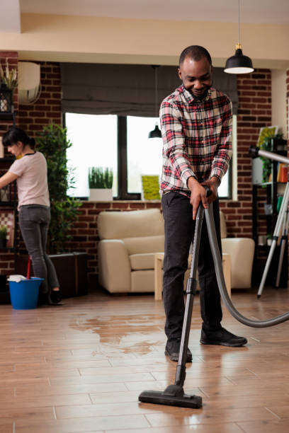 istock Smiling African american man vacuuming the floor. 1437424193