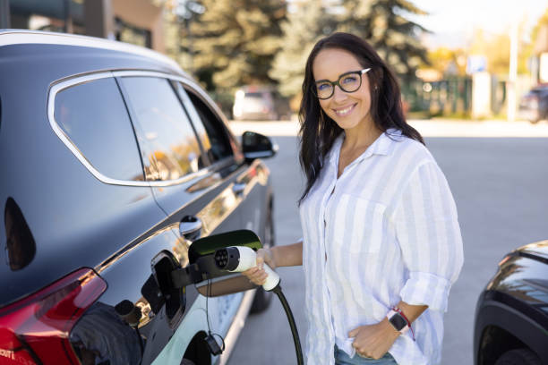 A young beautiful woman is charging her electric car in a charging station. stock photo