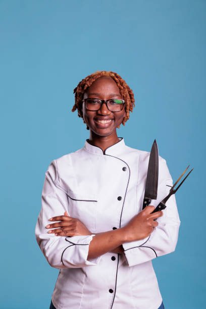 istock Smiling afro chef holding kitchen utensils 1437426345