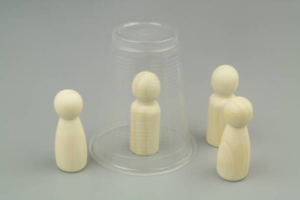 istock Wooden people figures on gray background. One figure under plastic cup. 1437428433