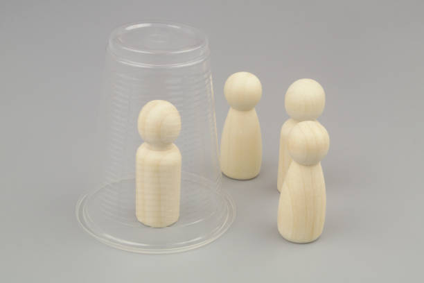 istock Wooden people figures on gray background. One figure under plastic cup. 1437428441