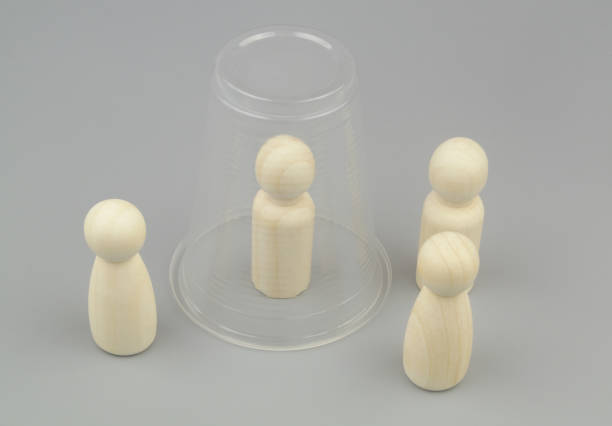 istock Wooden people figures on gray background. One figure under plastic cup. 1437428452