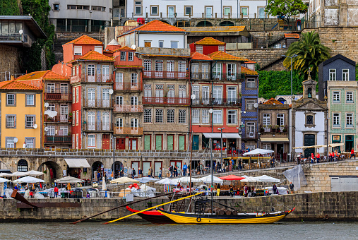 Porto, Portugal - May 30, 2018: Facades of traditional houses with azulejo tile in Ribeira and tourist rabelo boat docked on Douro in Porto Portugal