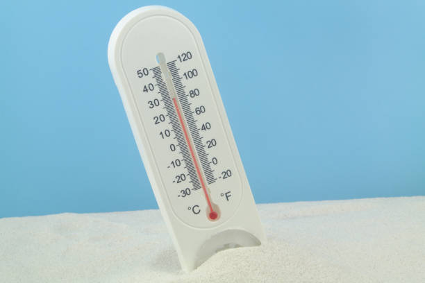 istock Thermometer on white sand against blue background. 1437434957