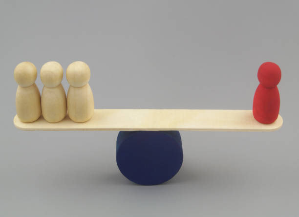 istock Red colored and ordinary wooden people figures on seesaw. 1437435298