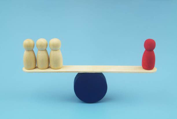 istock Red and ordinary wooden people figures on seesaw. 1437436258