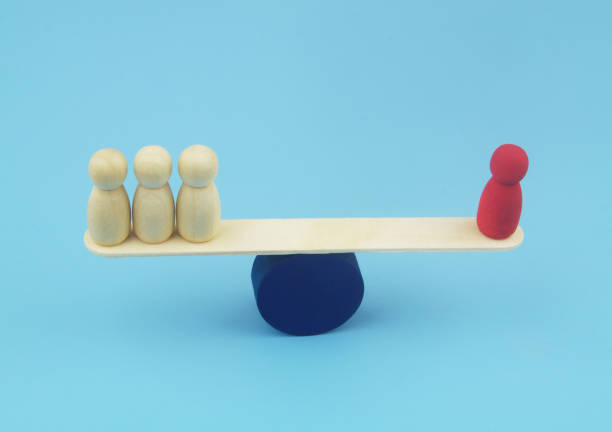 istock Red and ordinary wooden people figures on seesaw. 1437436267