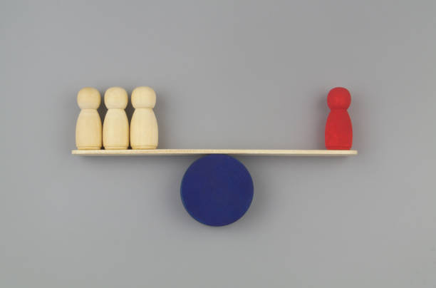istock Red colored and ordinary wooden people figures on seesaw. 1437436278