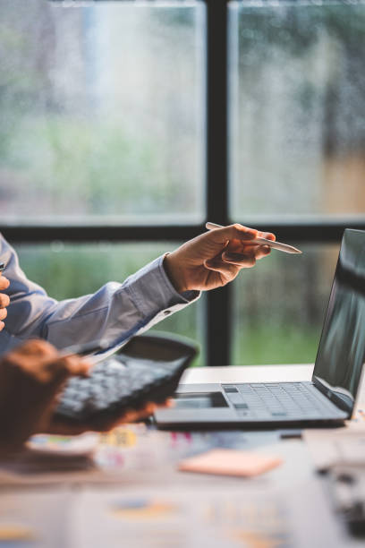 istock Young colleagues discuss business and analytical price charts using calculators and laptops to calculate financial, tax, accounting, statistics and analytical research ideas. 1437436415