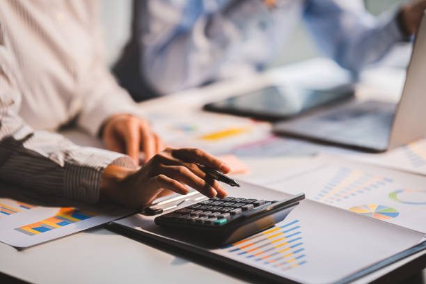 istock Young colleagues discuss business and analytical price charts using calculators and laptops to calculate financial, tax, accounting, statistics and analytical research ideas. 1437436420
