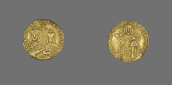 A top view of two gold coins isolated on gray surface background