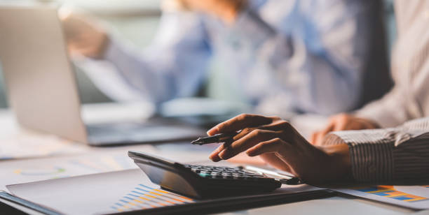 istock Young colleagues discuss business and analytical price charts using calculators and laptops to calculate financial, tax, accounting, statistics and analytical research ideas. 1437436627