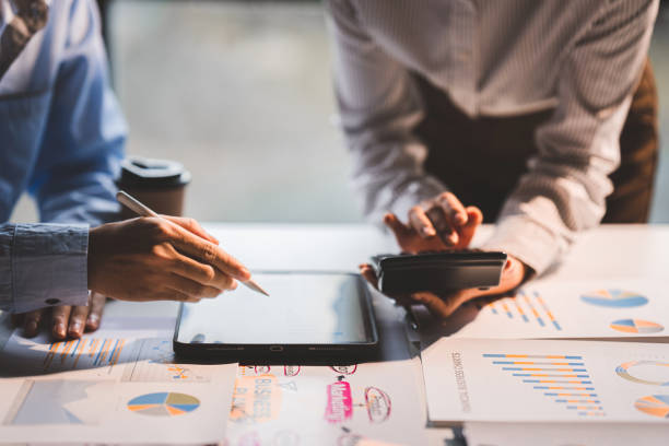 istock Young colleagues discuss business and analytical price charts using calculators and laptops to calculate financial, tax, accounting, statistics and analytical research ideas. 1437436631