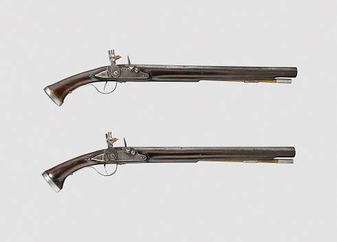 A pair of vintage pistols or muskets on a white bac