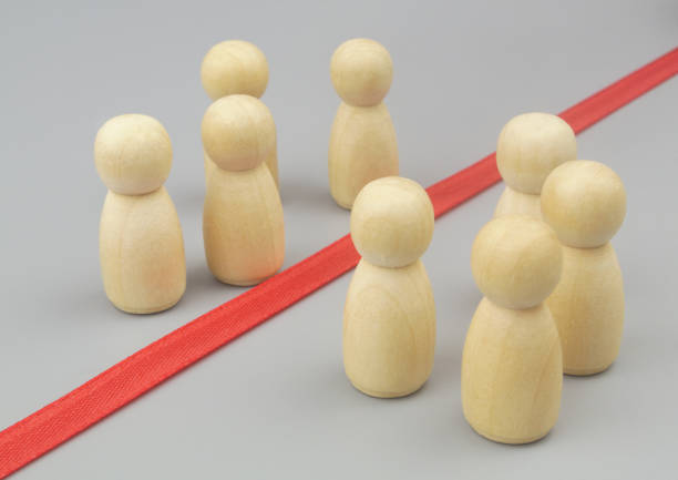 istock Wooden figures separated by red ribbon as border. 1437439031