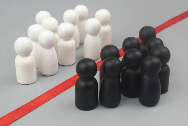 Groups of white and black people figures separated by red line on gray background. stock photo