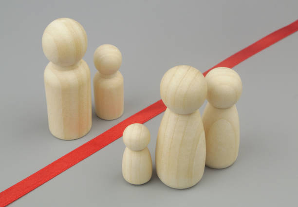 istock Father with son wooden figures separated from wife and daughters figures. Problems with visas for family members and citizenship concept. 1437439076