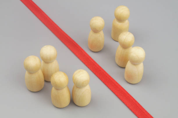 istock Wooden figures separated by red ribbon as border. 1437439077