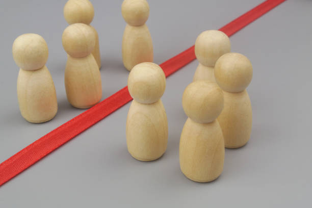 istock Wooden figures separated by red ribbon as border. 1437439142