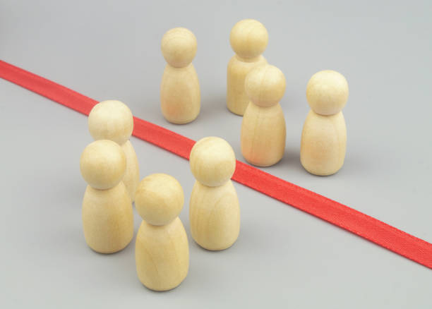 istock Wooden figures separated by red ribbon as border. 1437439151