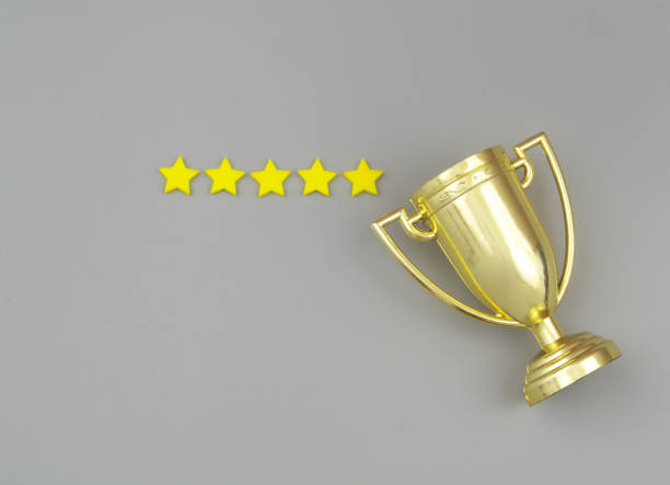Gold champion trophy cup with five stars on gray background. stock photo