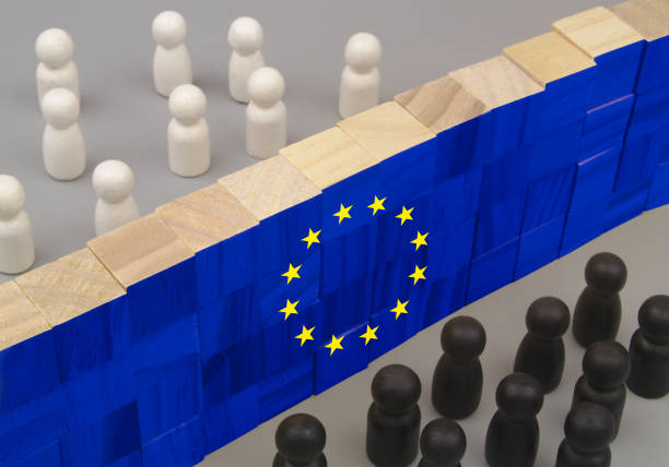 istock White and black people figures separated by high wall with EU flag on gray background. 1437440528
