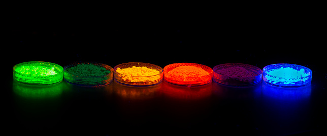 Fluorescent organic materials powder of red, yellow, green color for production OLED displays in UV light. Closeup.