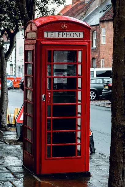 Photo of Vertical shot of a red telephone booth after rain on a street in London