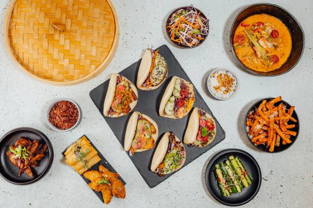 istock Top view of bao buns surrounded by different dishes on a white table 1437447383